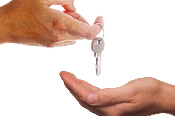 Hand passing a house key into another hand