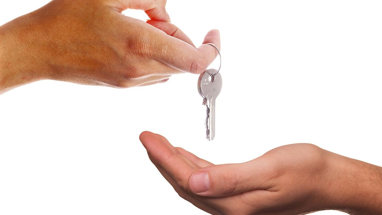 Hand passing a house key into another hand
