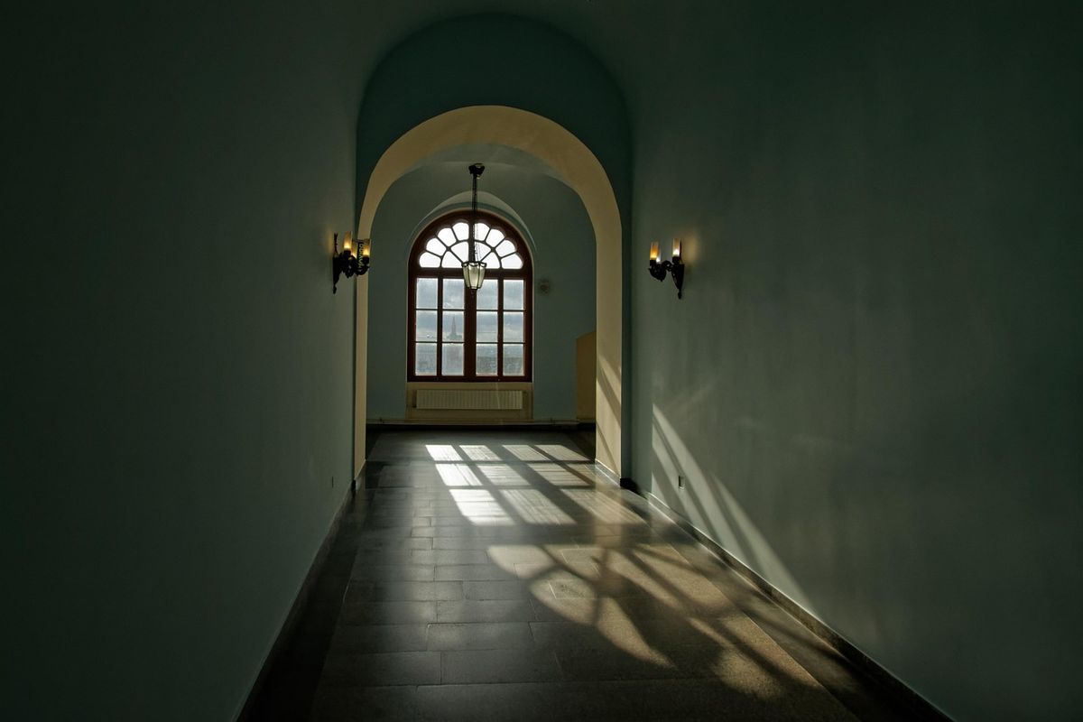 Sunlit arched corridor leading to a window