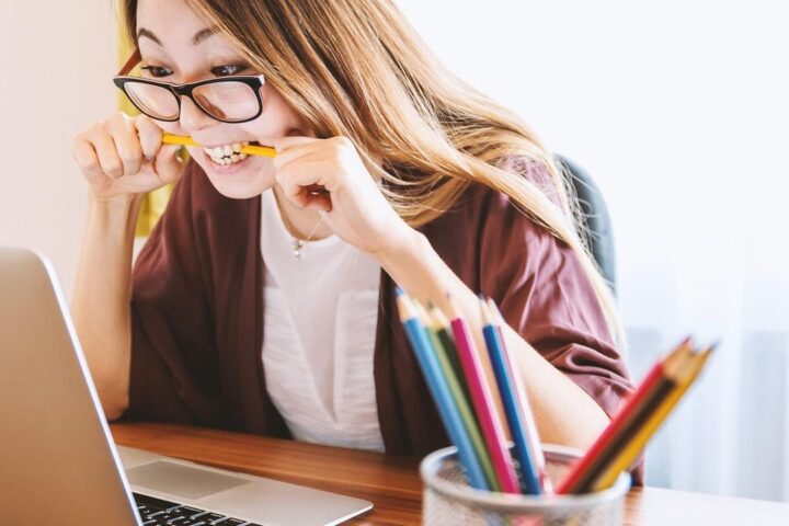 Young woman studying with coloured pencils and a laptop