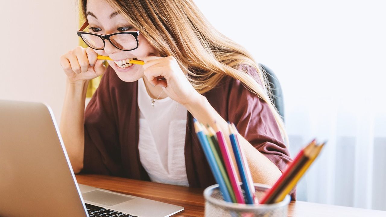 Young woman studying with coloured pencils and a laptop