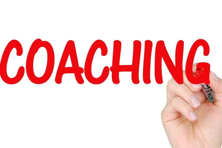 Hand writing the word Coaching in red