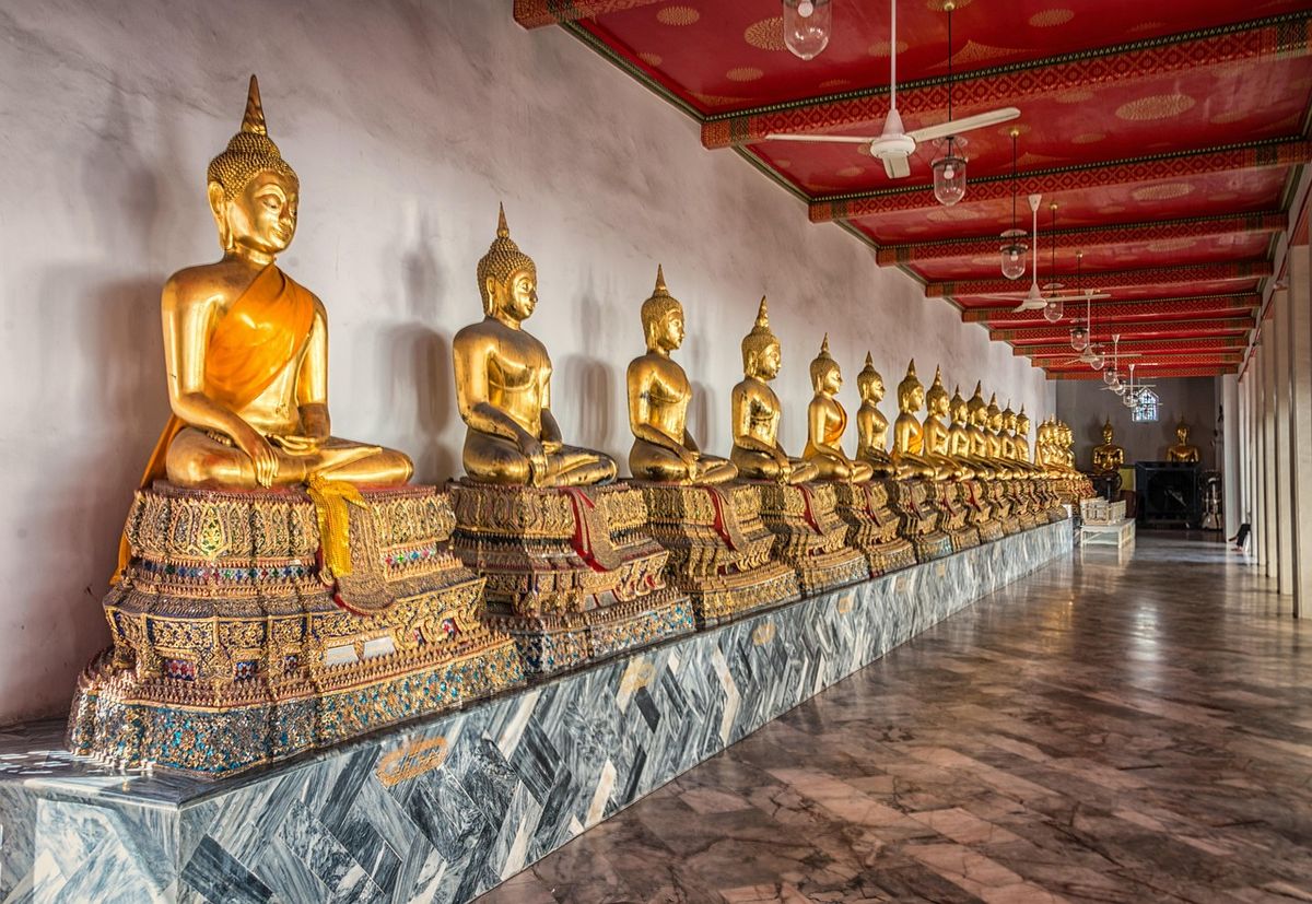 Row of golden Buddha statues in a temple gallery