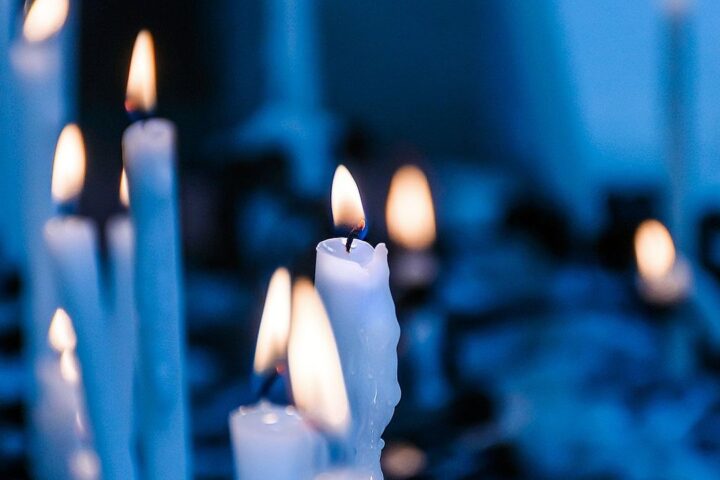 Lit white candles in soft blue light