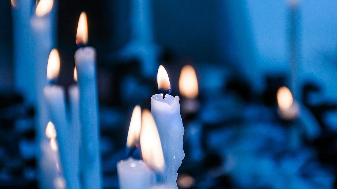 Lit white candles in soft blue light