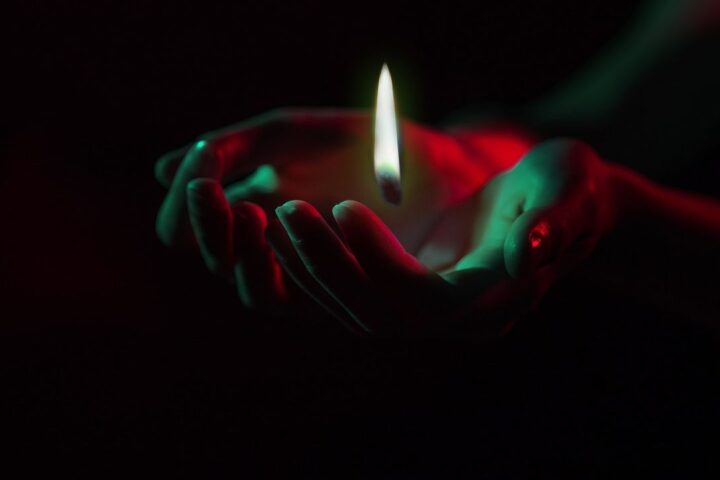 Cupped hands holding a candle flame