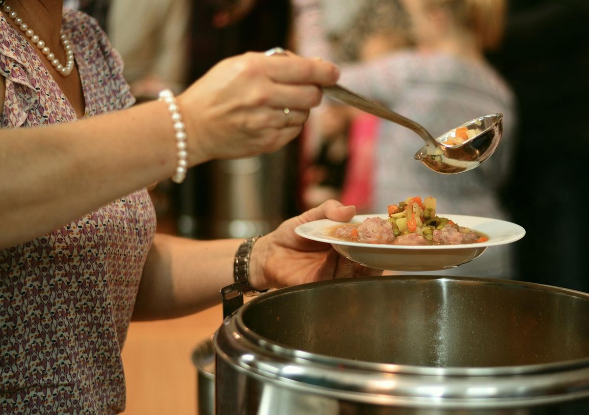 Volunteer serving soup from a large pot