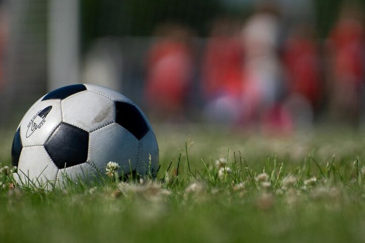 Football resting on grass in front of a blurred crowd
