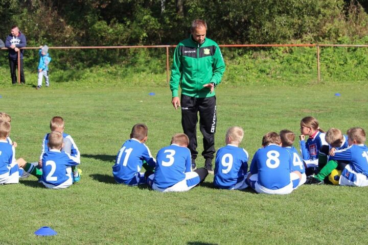 Coach talking to a youth football team sitting on the grass