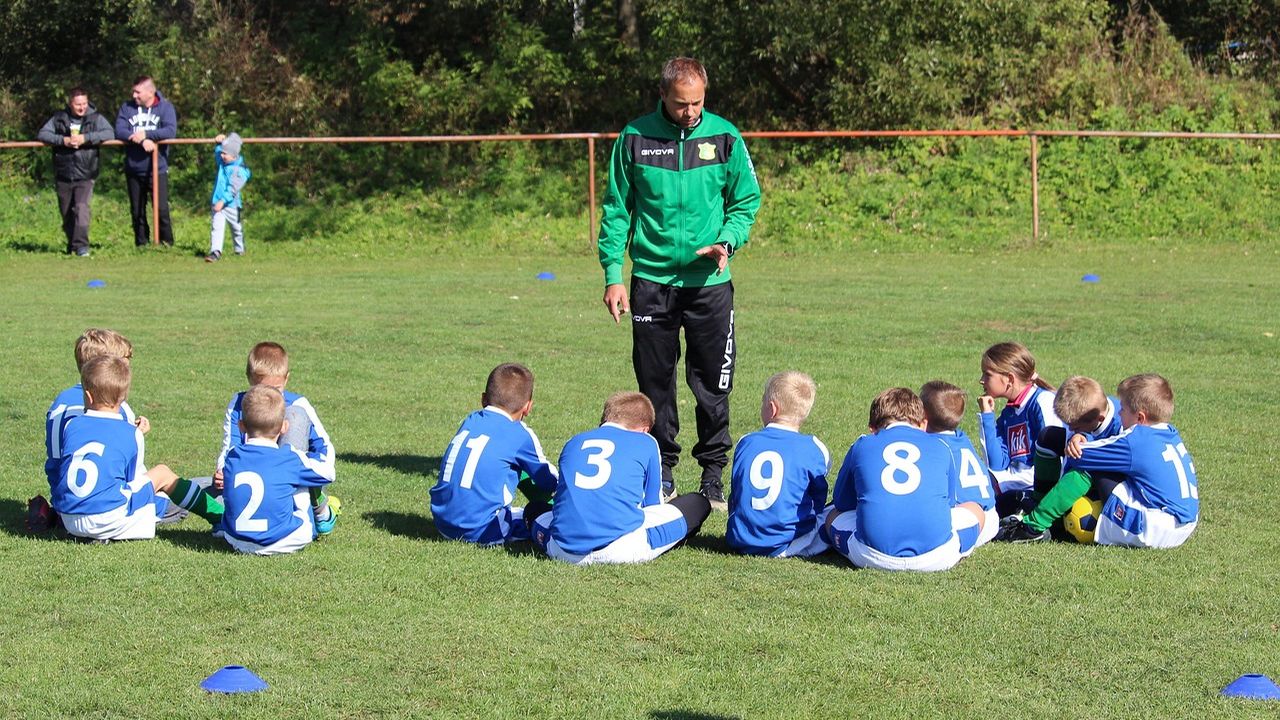 Coach talking to a youth football team sitting on the grass