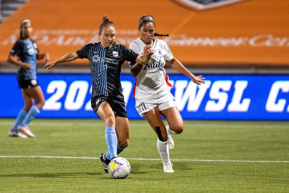 Two women footballers chasing the ball in a professional match
