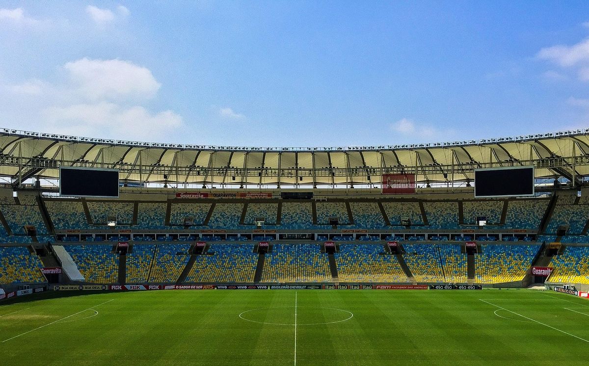 Empty football stadium with green pitch and stands