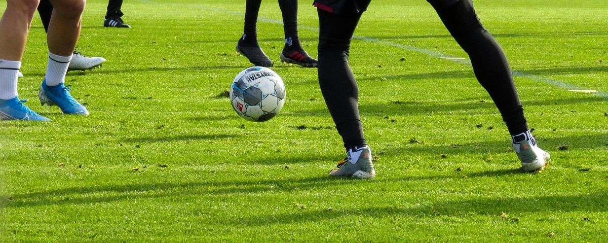 Players' feet chasing a ball on the grass
