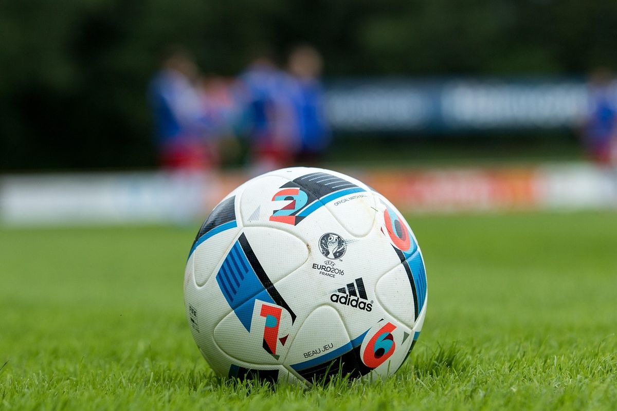 Football on the grass with players training in the background