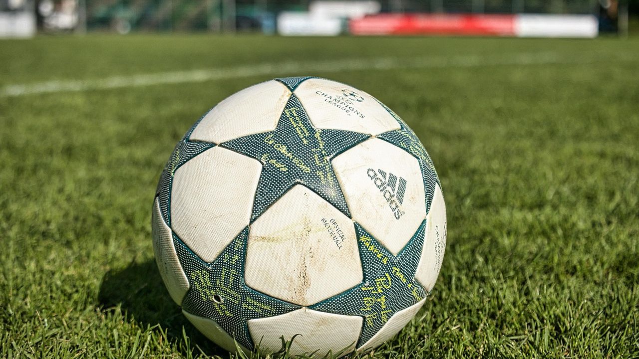 Star-patterned football resting on a grass pitch