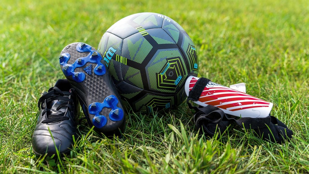 Football boots, shin pads and a ball on the grass