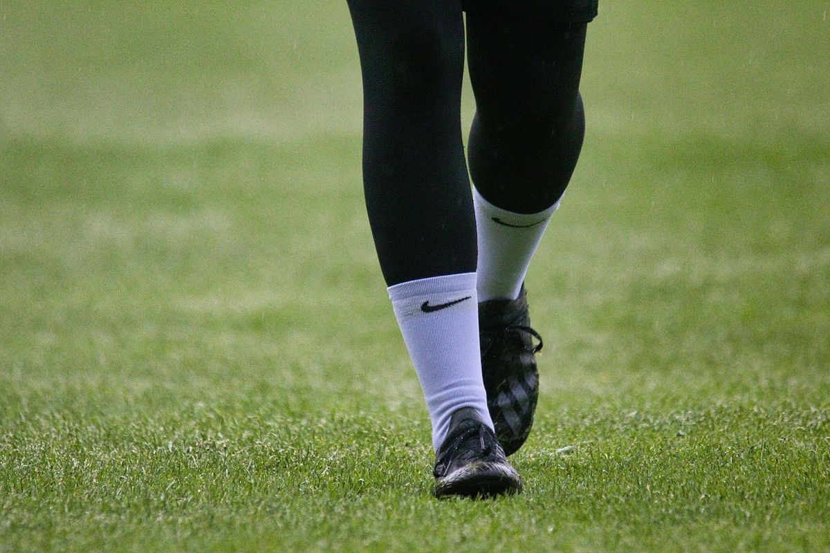 Close-up of a player's football boots and socks on grass