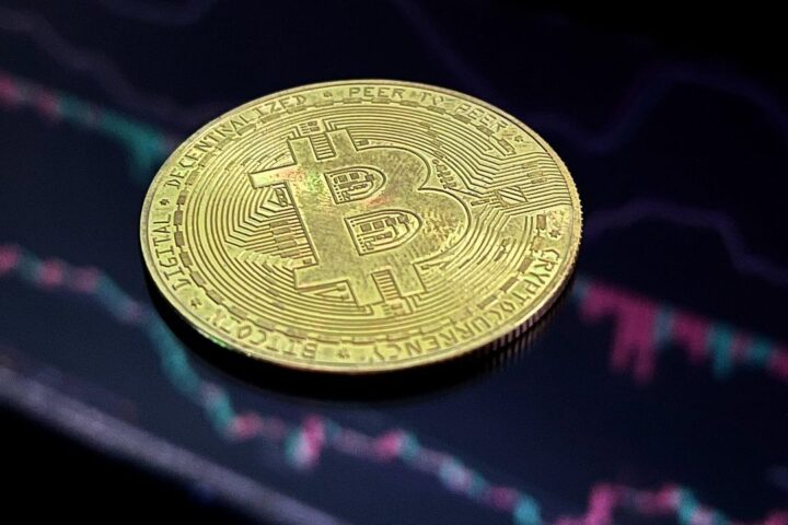 Bitcoin coin lying on a dark trading chart
