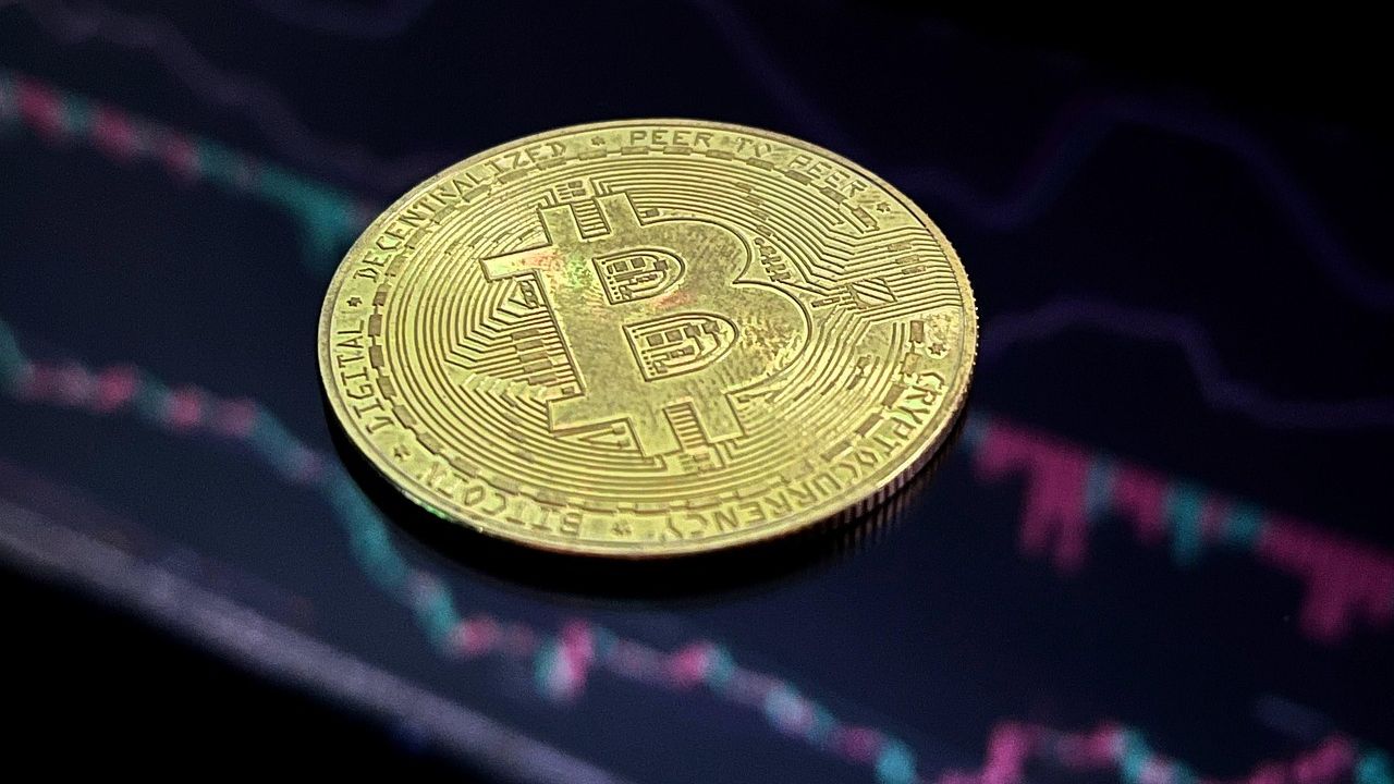 Bitcoin coin lying on a dark trading chart