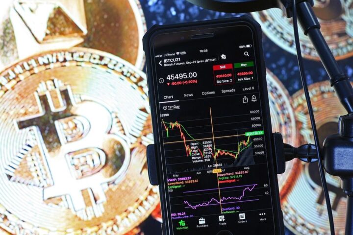 Bitcoin coins beside a phone showing a trading chart