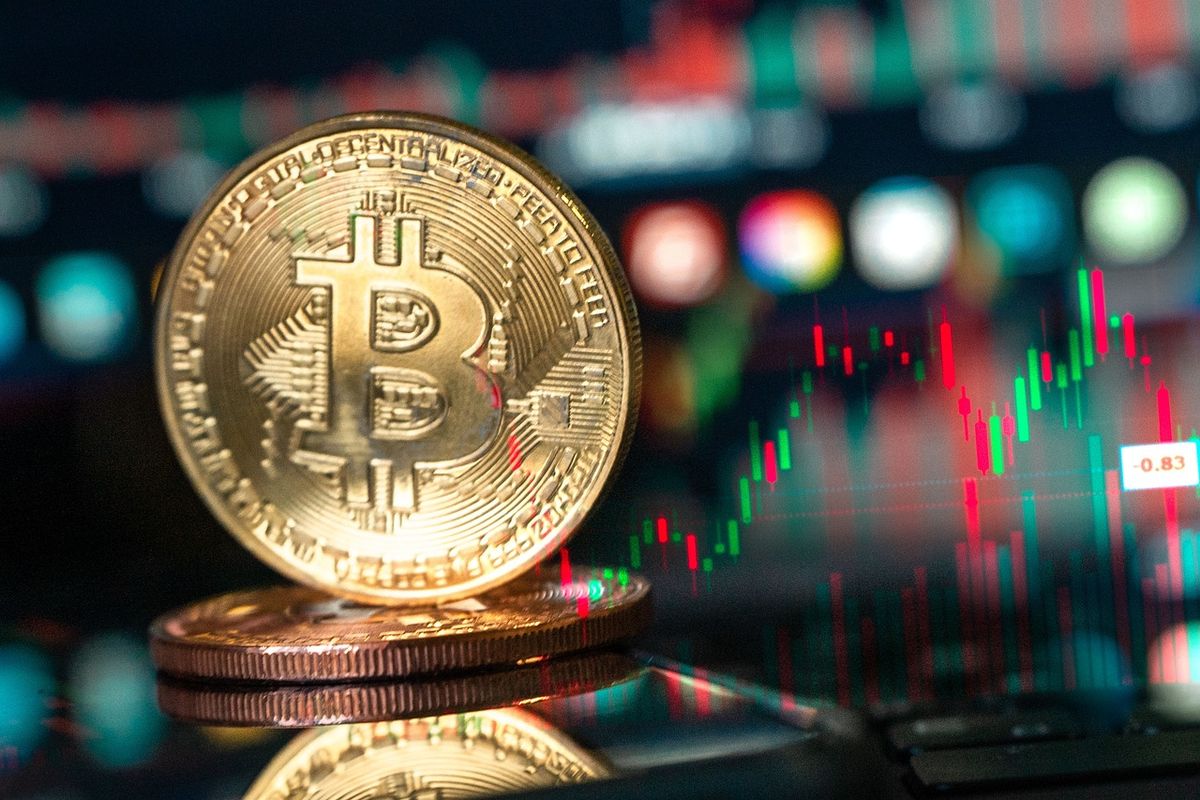 Gold bitcoin coin in front of glowing market charts
