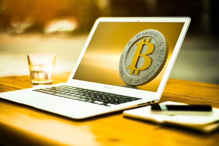 Laptop showing a bitcoin symbol on a sunlit desk