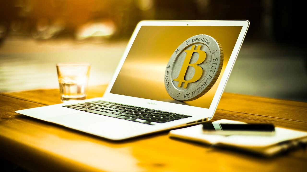 Laptop showing a bitcoin symbol on a sunlit desk