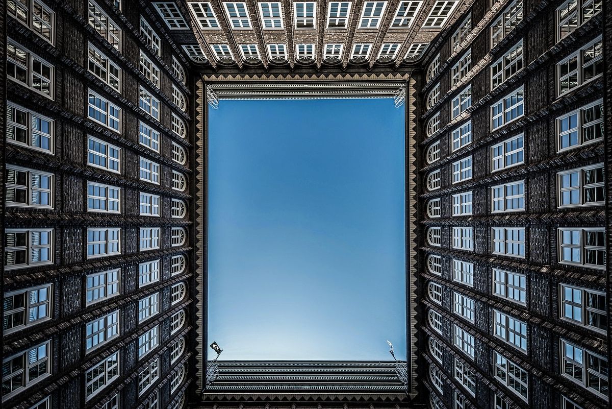 Looking up at the sky from inside a tall courtyard