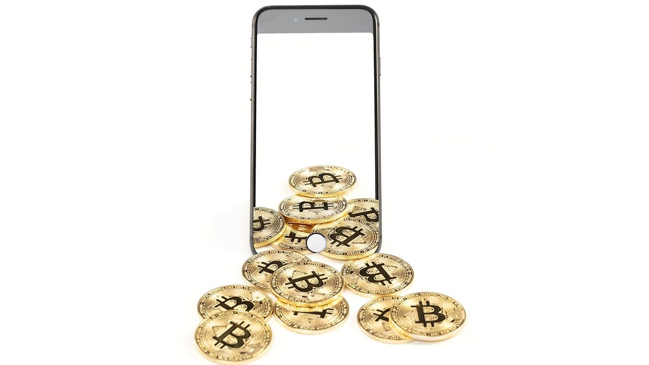 Pile of bitcoin coins spilling out of a smartphone