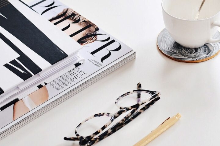 Fashion magazines, glasses and a cup of tea on a table