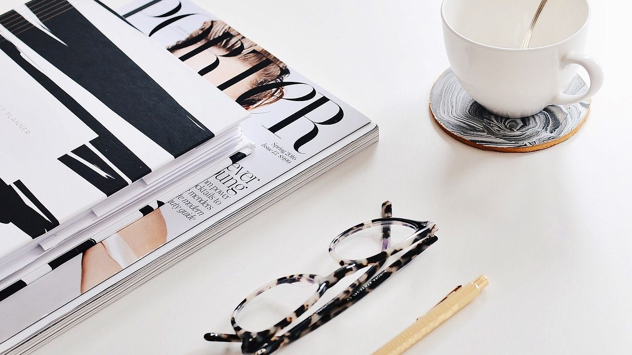 Fashion magazines, glasses and a cup of tea on a table