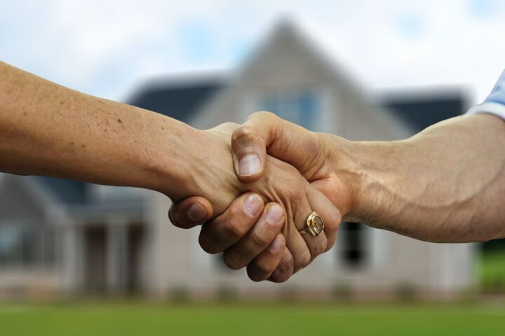 Handshake in front of a blurred family home