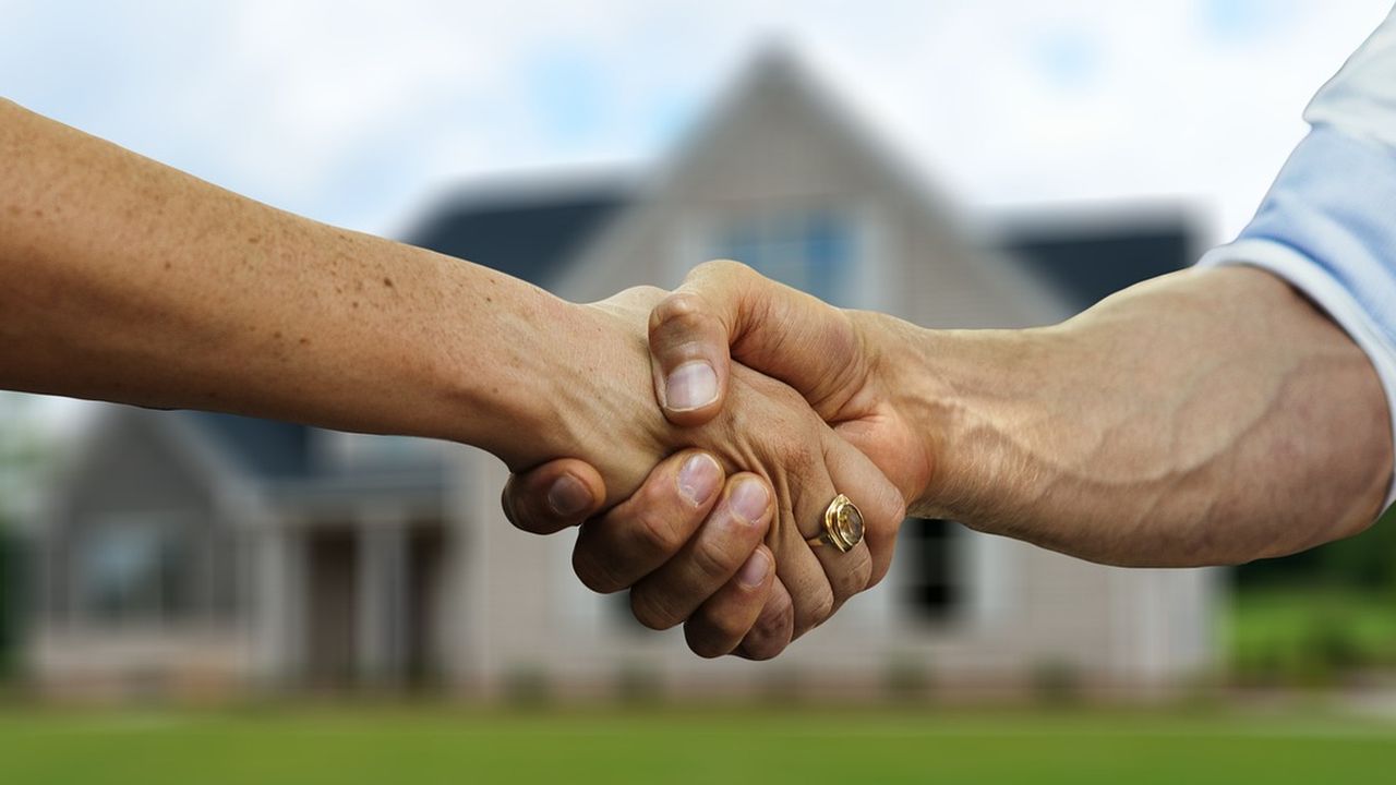 Handshake in front of a blurred family home
