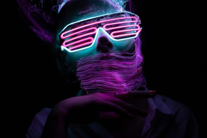 Person wearing glowing neon glasses in the dark