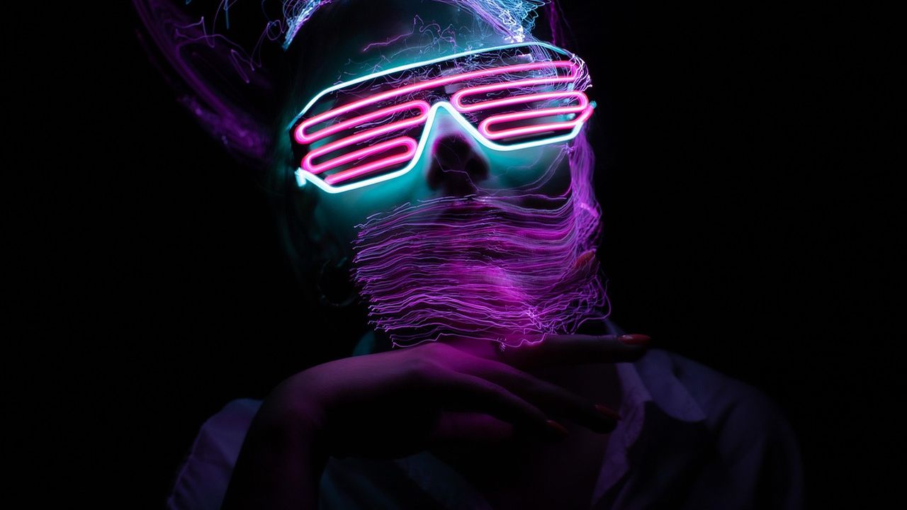 Person wearing glowing neon glasses in the dark