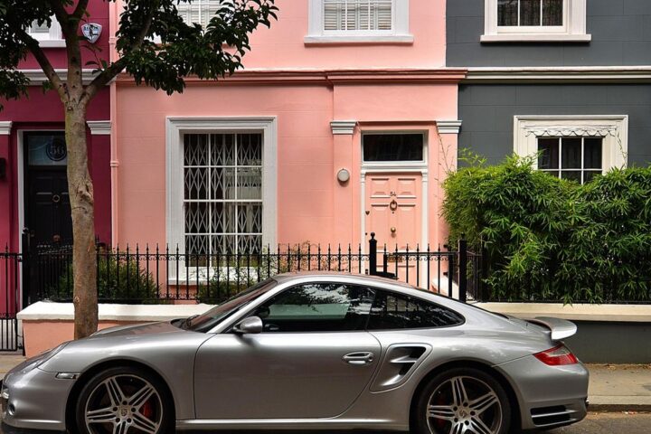Pastel-painted London terraced houses with a sports car outside