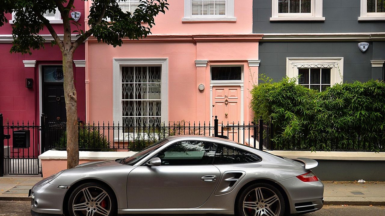 Pastel-painted London terraced houses with a sports car outside