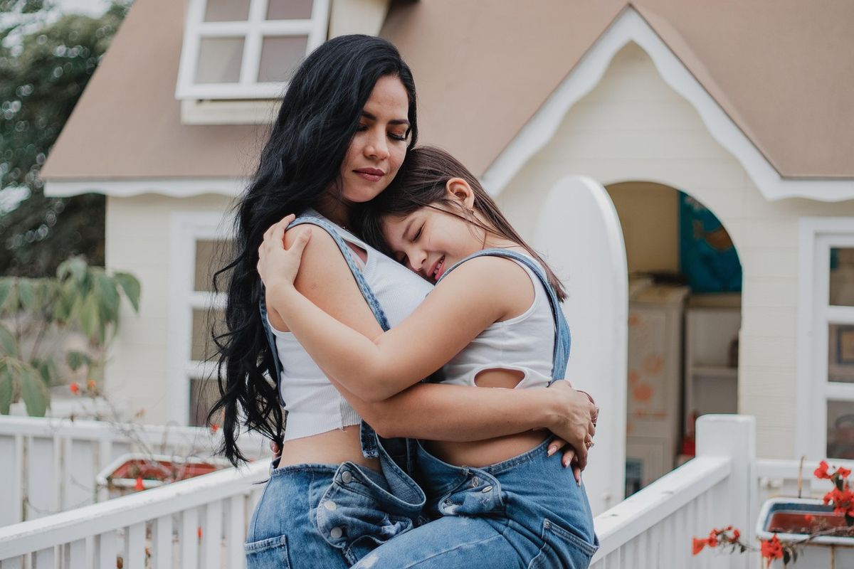 Mother and daughter hugging on the porch of their home