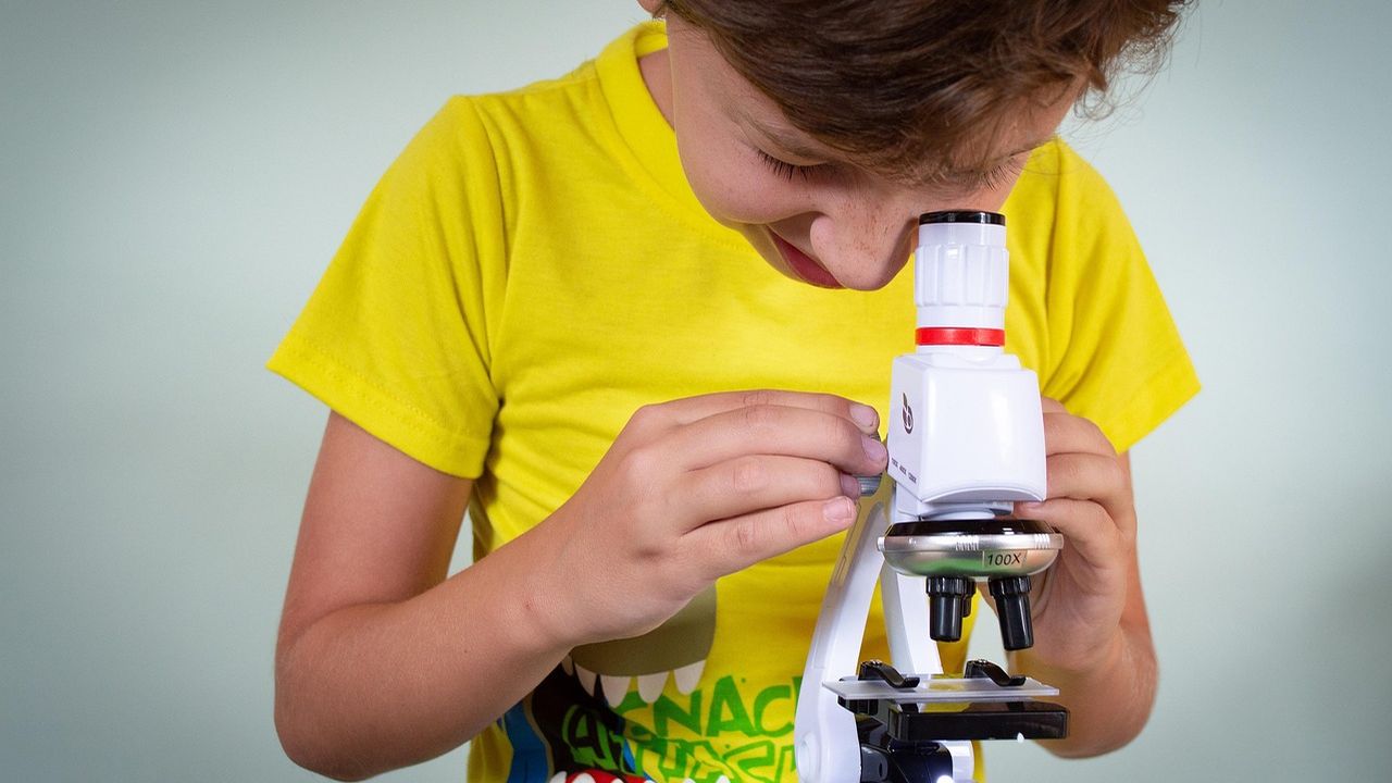 Boy in a yellow T-shirt looking through a toy microscope