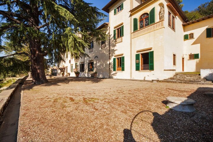 Façade of Villa Michele with green shutters and a gravel courtyard