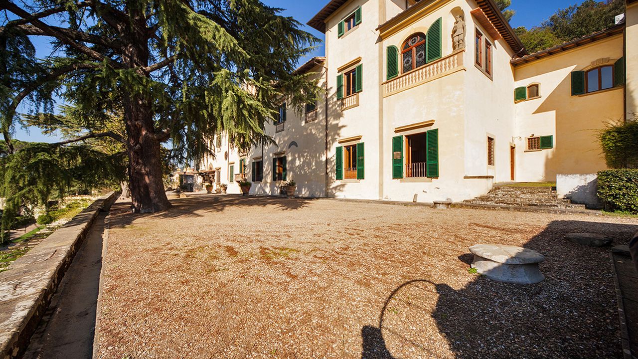 Façade of Villa Michele with green shutters and a gravel courtyard