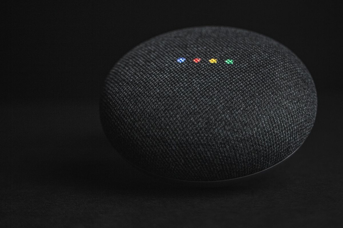 Smart speaker with coloured lights on a dark surface