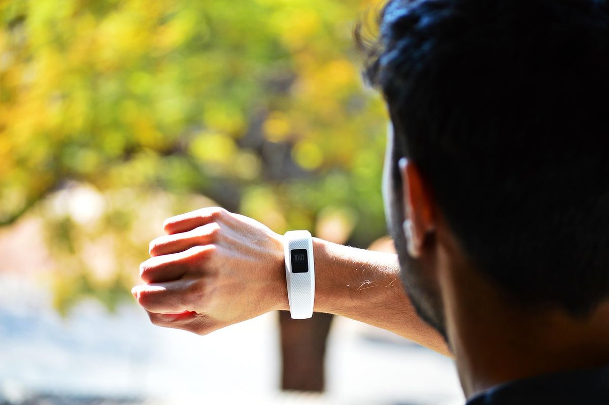 Man checking a white fitness tracker on his wrist