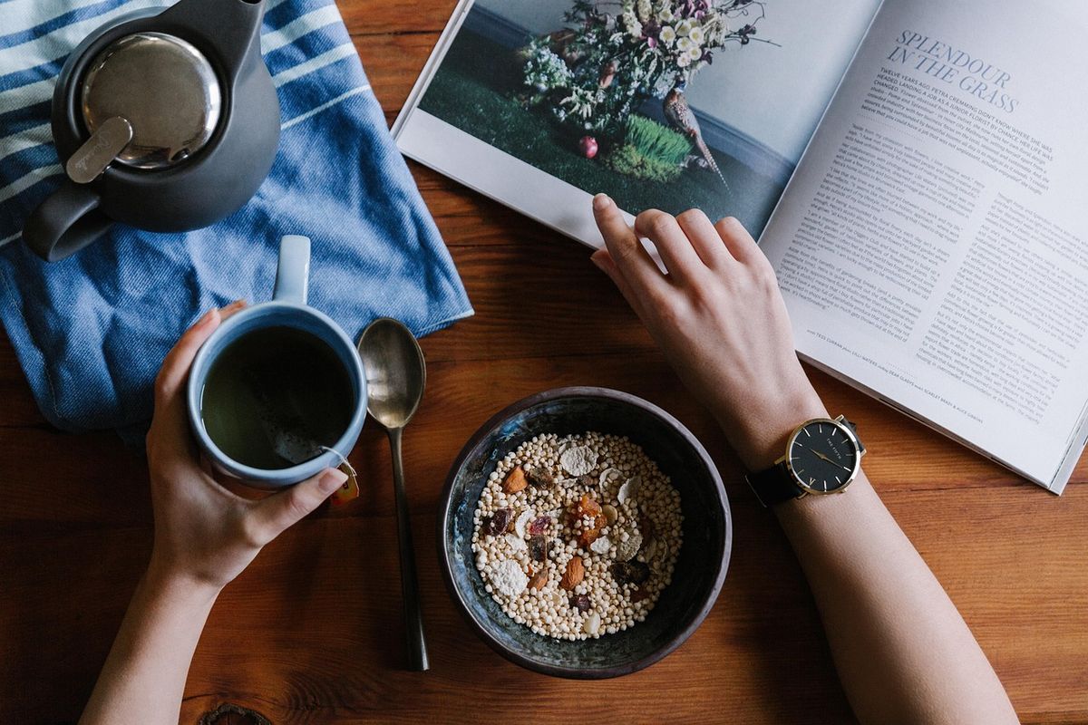 Hands holding a mug beside an open magazine