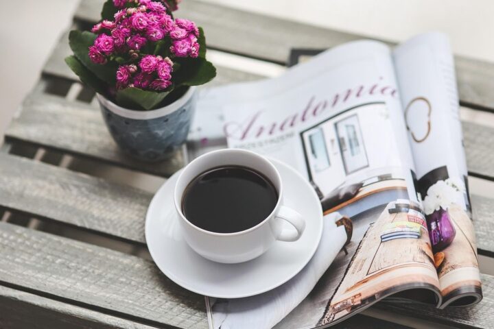 Magazine and coffee on a wooden table with flowers