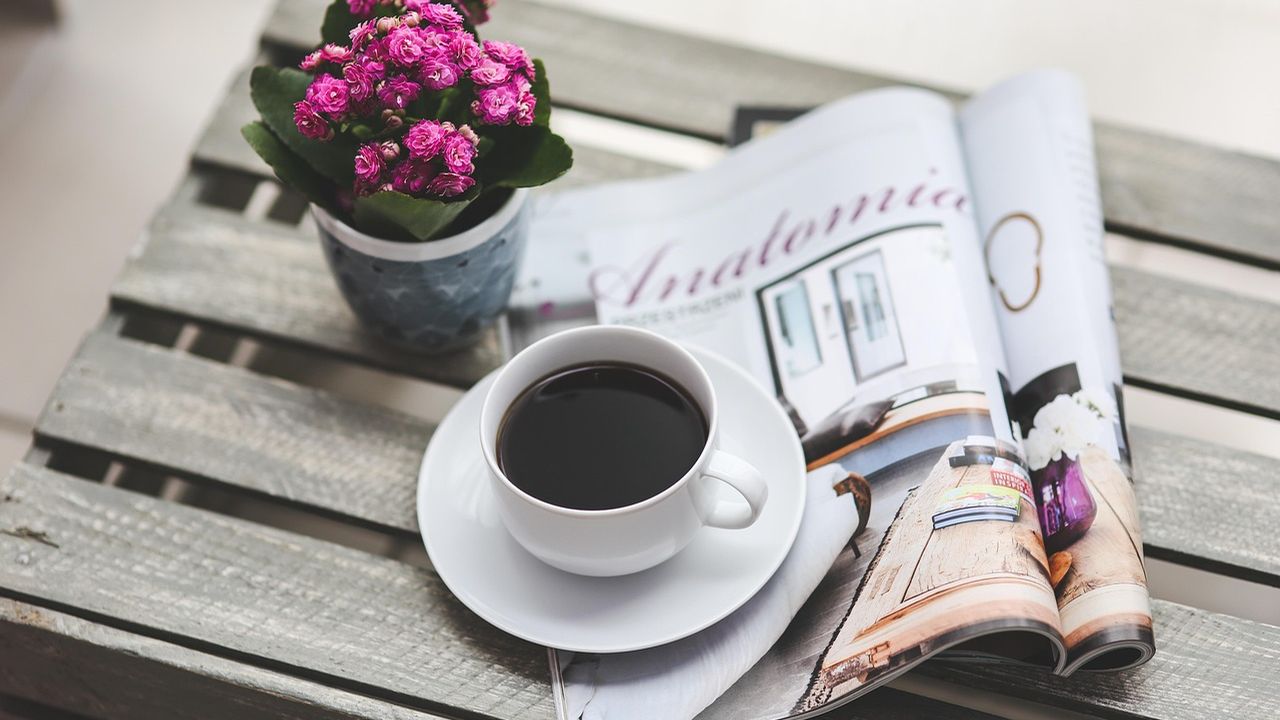 Magazine and coffee on a wooden table with flowers
