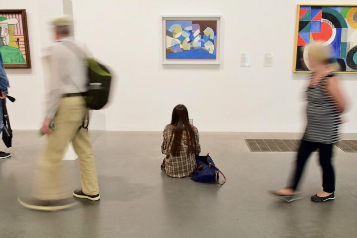 Visitors walking past colourful abstract paintings in a gallery