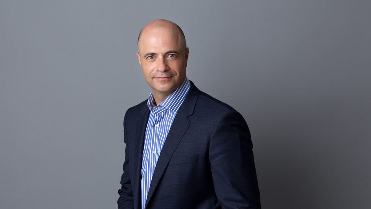 Portrait of a man in a navy suit against a grey background