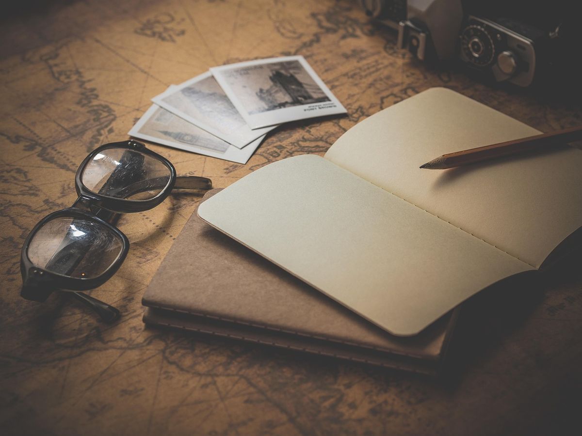 Notebook, glasses and old photos on a wooden table