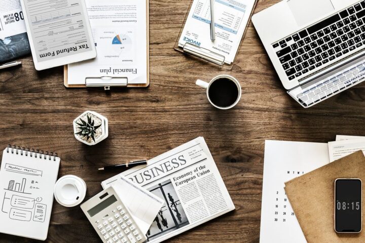 Desk spread with charts, a laptop and a business newspaper